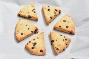 Six triangular Keto Chocolate Chip Scones arranged in a circle on a sheet of parchment paper.