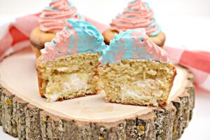 3 cupcakes on a wooden board with one cut in half