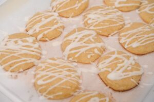 A batch of freshly baked Keto Italian Lemon Cookies drizzled with white icing on a serving tray.
