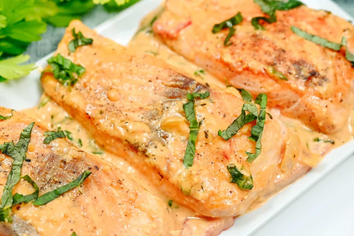 Succulent Creamy Tuscan Salmon garnished with fresh herbs on a white plate, ready to be served.