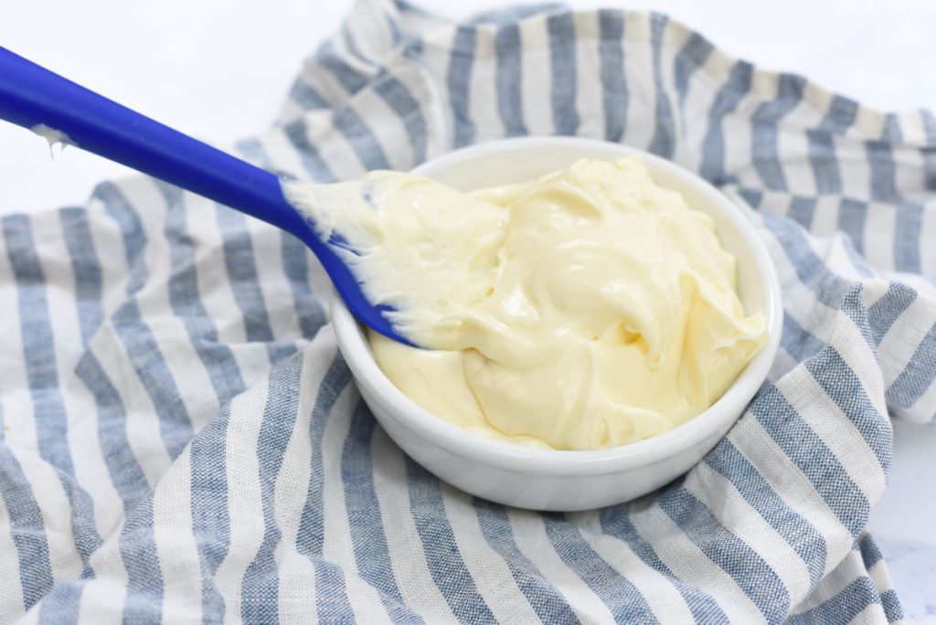 Cream cheese frosting in a white bowl with a spatula.