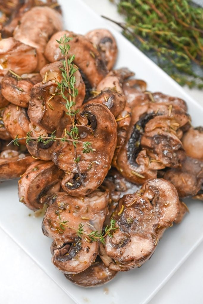 A plate of marinated mushrooms on a white plate.