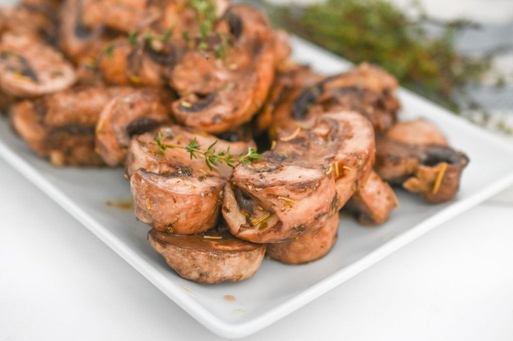 A plate of marinated mushrooms on a white plate.