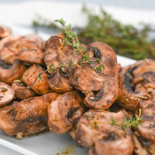A plate of marinated mushrooms on a white plate.