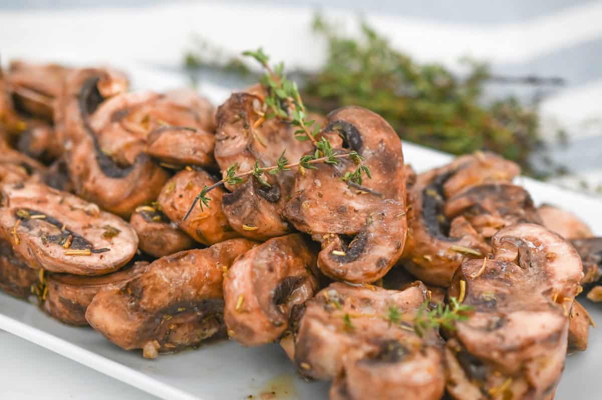 A plate of marinated mushrooms on a white plate.