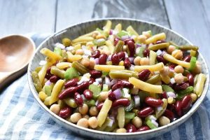 4 Bean Salad in a bowl with a wooden spoon.