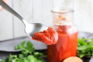 BBQ Sauce on a spoon with a jar in the back.