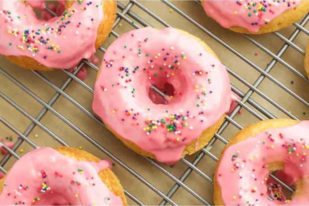 Vanilla Donuts With Raspberry Glaze on a rack.