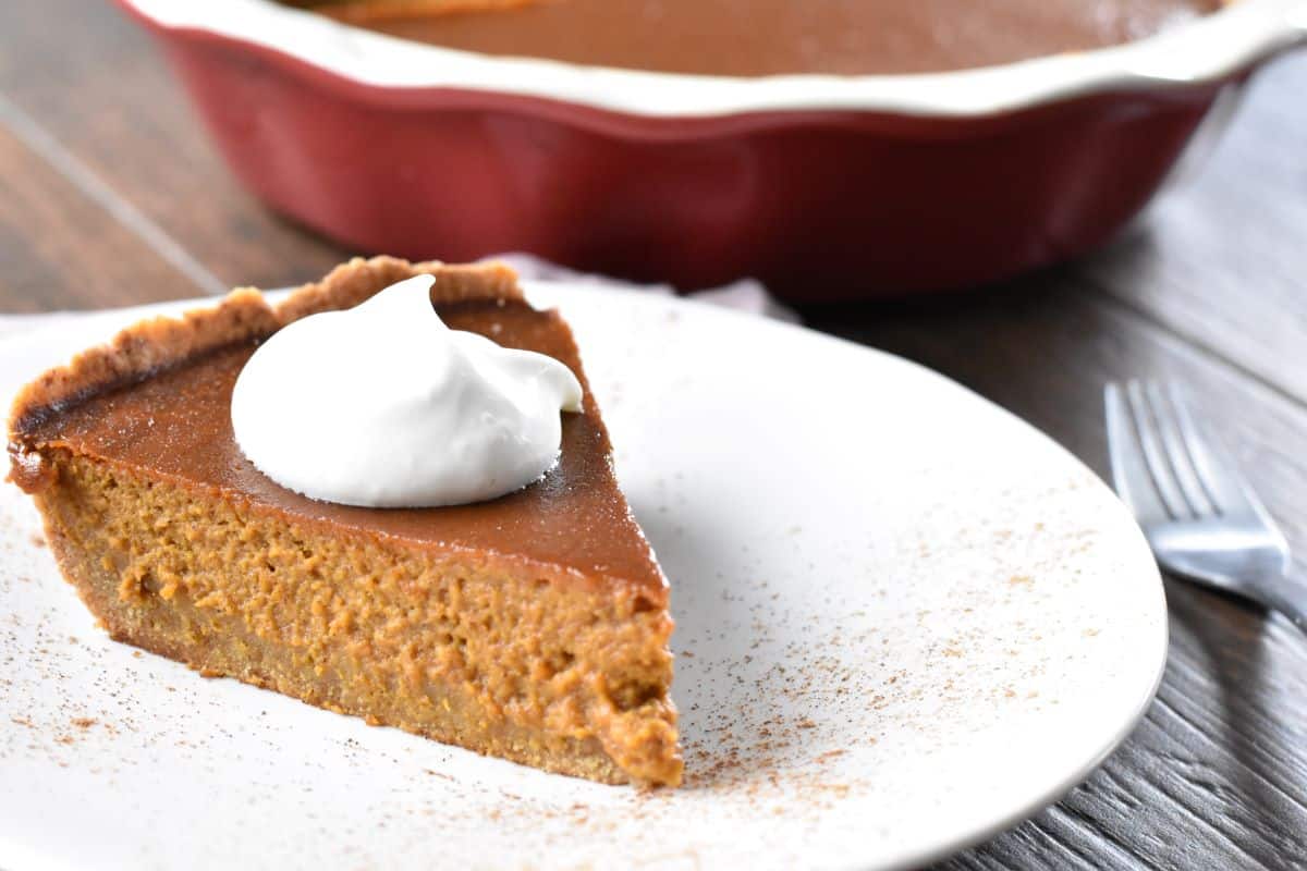 A slice of pumpkin pie om a white plate.
