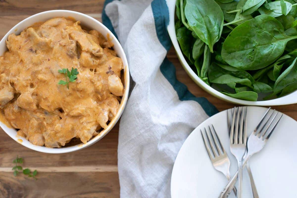 Instant Pot Chicken Paprika in a white bowl with salad.
