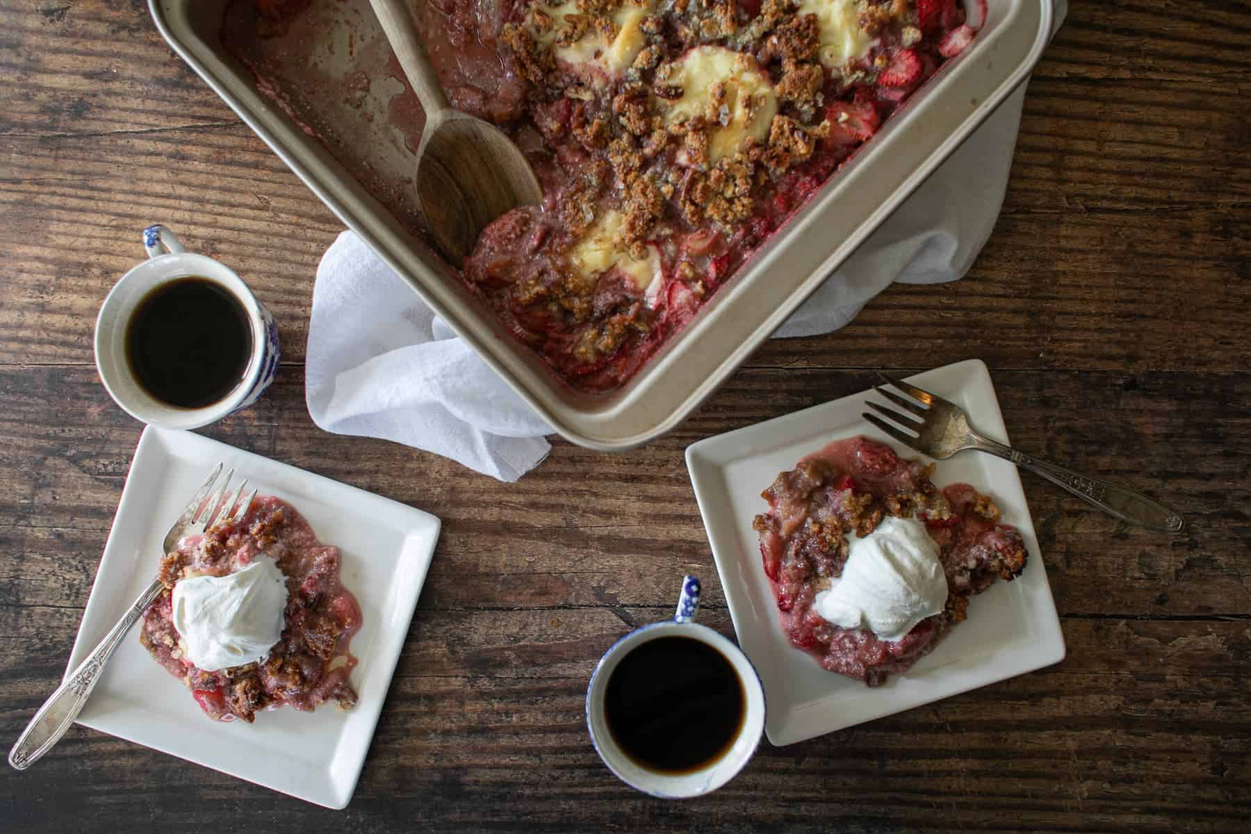 Strawberry Rhubarb Crisp in a pan with two slices on plates.