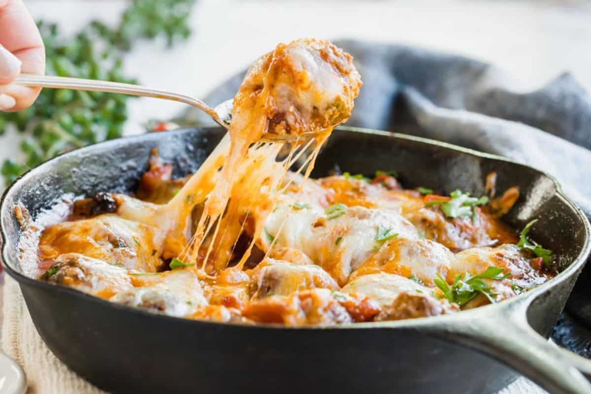 Meatballs in a skillet with cheese. 