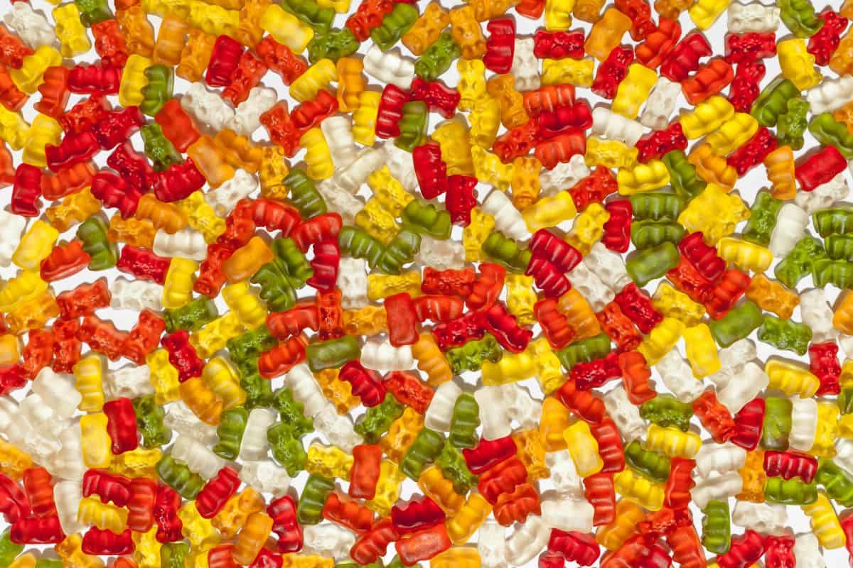 A colorful assortment of glossy, translucent gummy bears in red, orange, yellow, green, and white are scattered across a surface. Perfect for those seeking keto-friendly Halloween hacks to add a sweet yet festive touch without breaking dietary commitments.