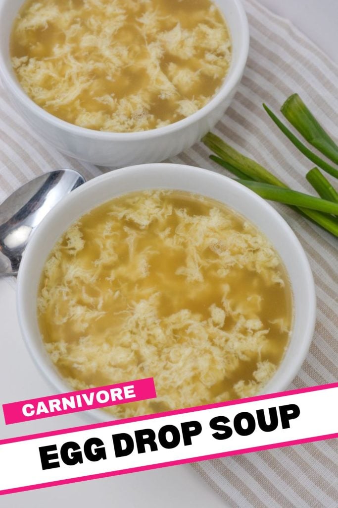 Two bowls of egg drop soup with a light broth and wisps of cooked egg. A spoon is placed beside the bowls on a striped cloth. Green onions are visible in the background. The image has "Carnivore Egg Drop Soup" text at the bottom.