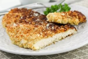 Crusted Chicken Romano cut open on a white plate.