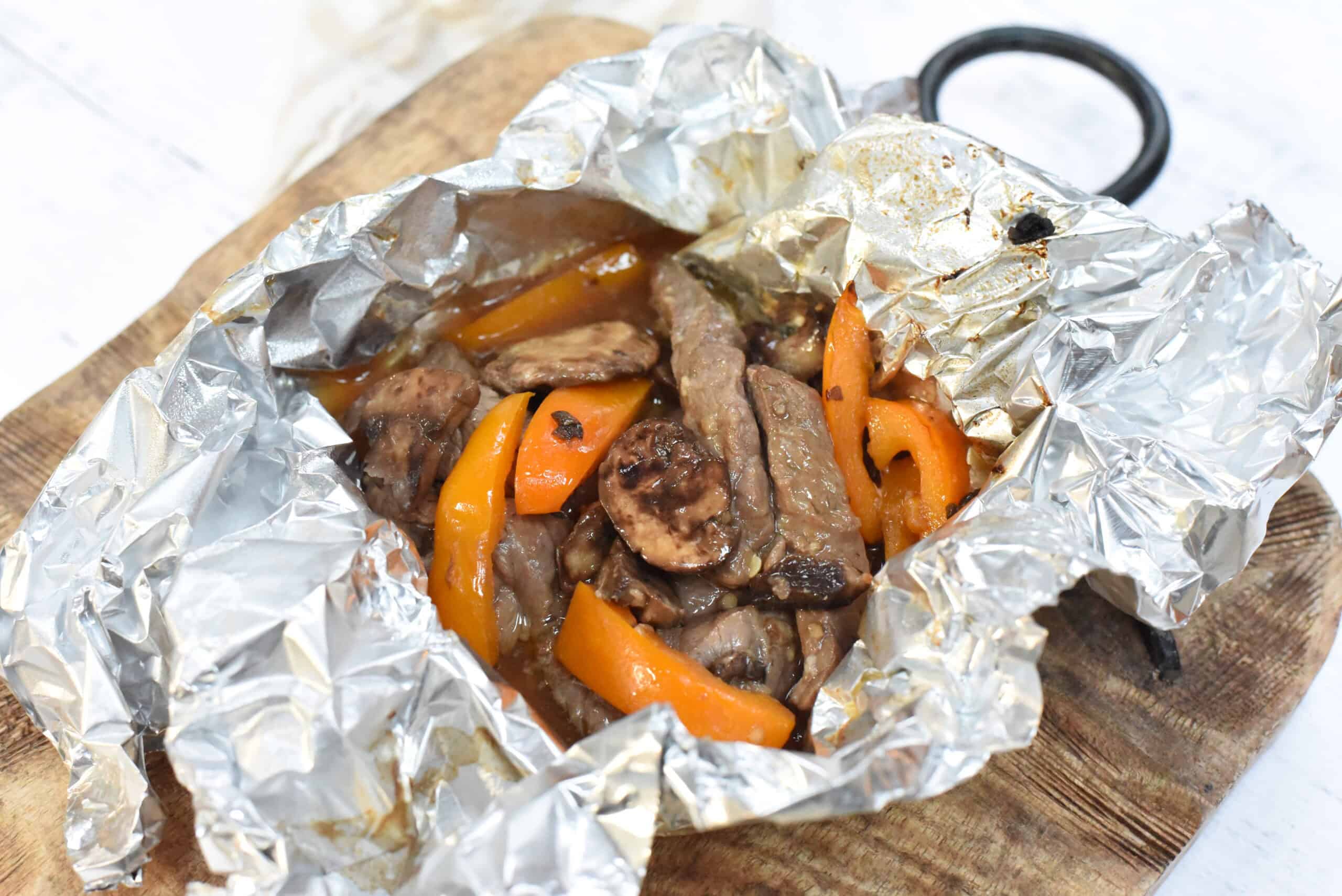 Marinated Steak and Mushroom Foil Packets on a wooden board.