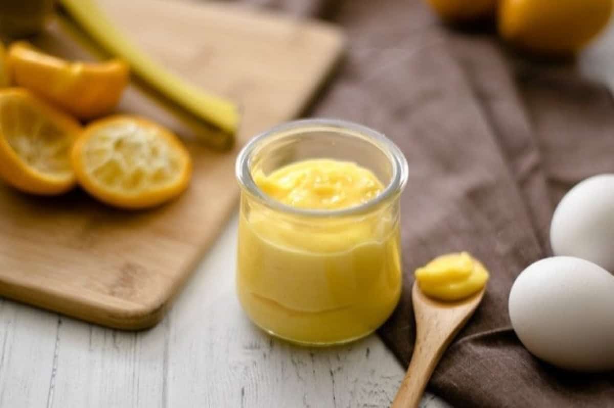 Lemon Curd in a mason jar with a wooden spoon.